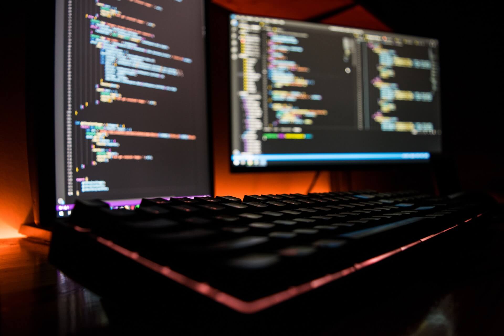 Two monitors with code on a dark desk